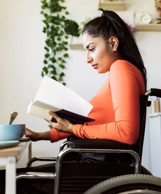 Young disabled woman reading book at home
