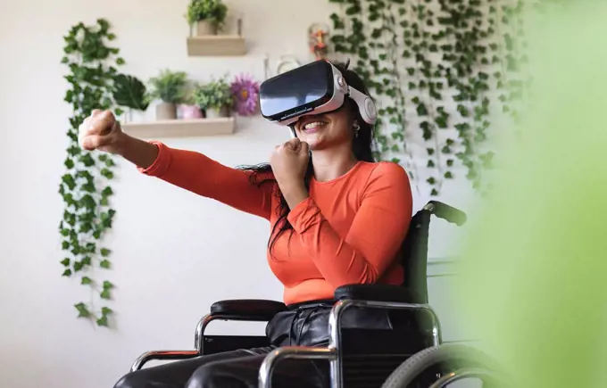 Smiling disabled woman wearing virtual reality headset gesturing at home