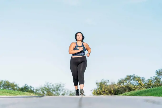 Plus size sportswoman running on road