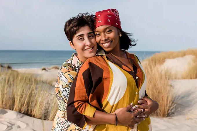 Affectionate lesbian couple embracing at beach on sunny day