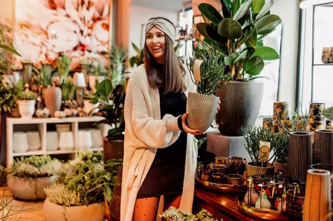 Smiling young woman buying potted plant at flower shop