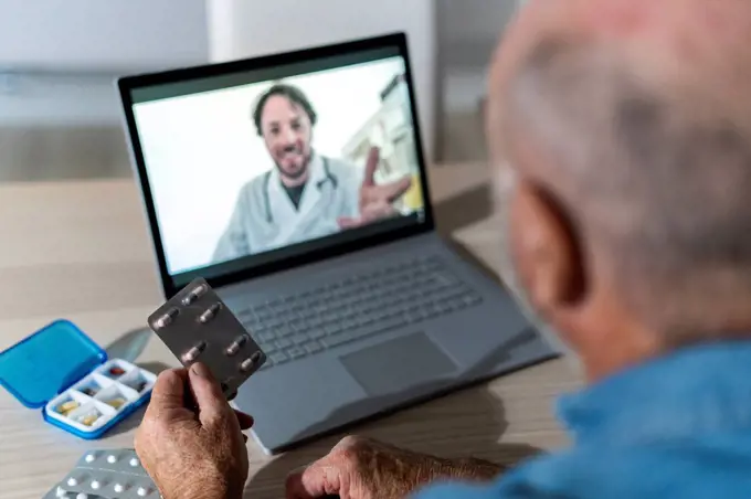 Senior man taking medical advice on video call with doctor at home