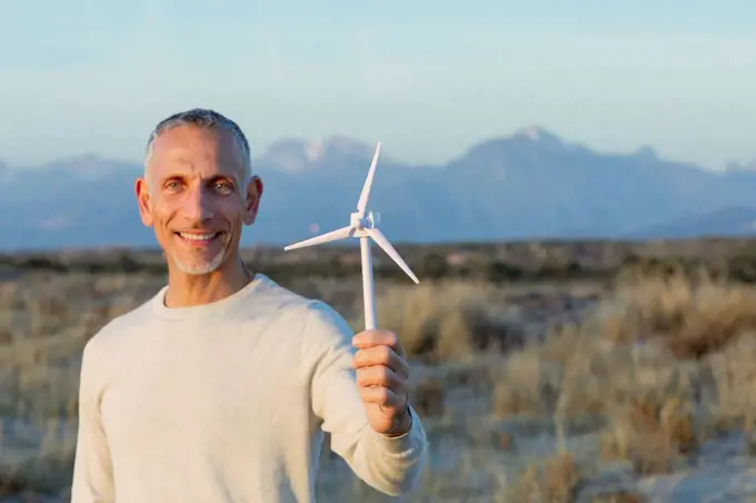 Smiling man holding wind turbine model
