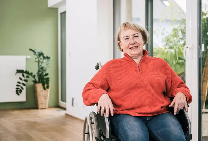 Smiling disabled woman in wheelchair at home