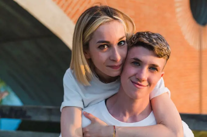 Blond woman hugging girlfriend from behind at sunset