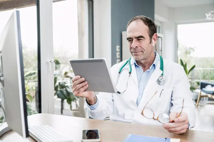 Doctor staring at digital tablet in medical clinic
