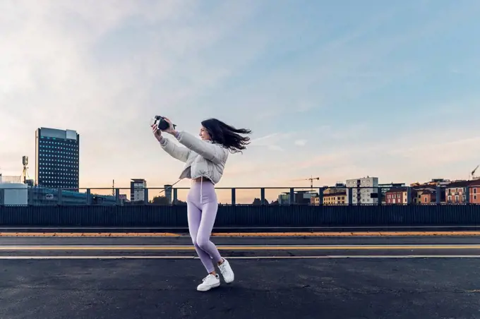 Influencer filming through camera on road at sunset