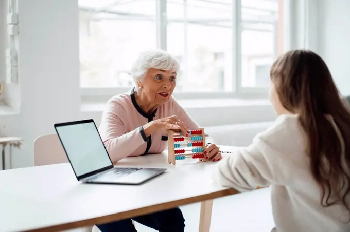 Grandmother with abacus talking to granddaughter at home