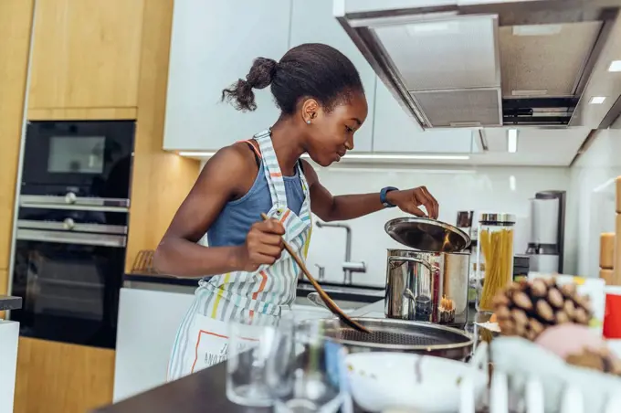 Pre-adolescent girl cooking food in kitchen