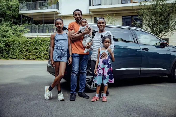 Family standing in front of car on road