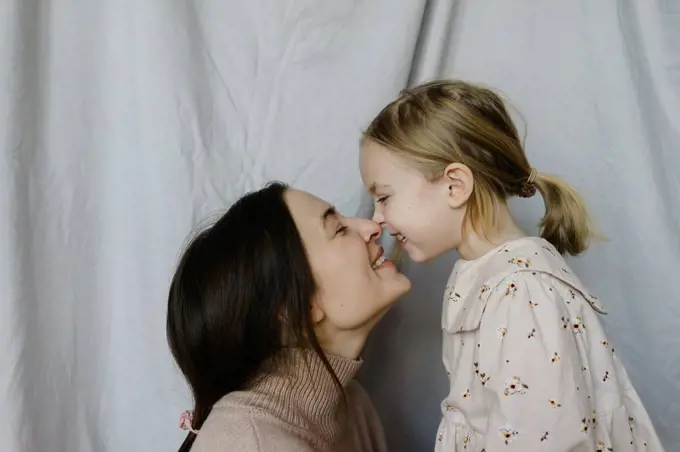 Happy mother and daughter with face to face at home