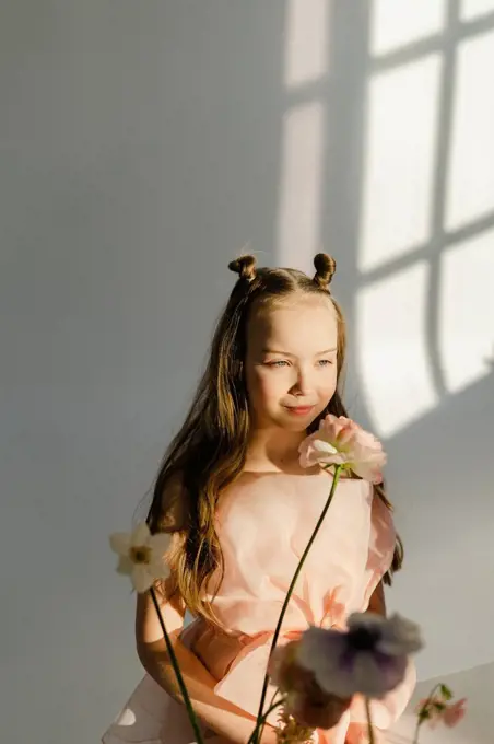 Girl with fresh flowers in front of white wall