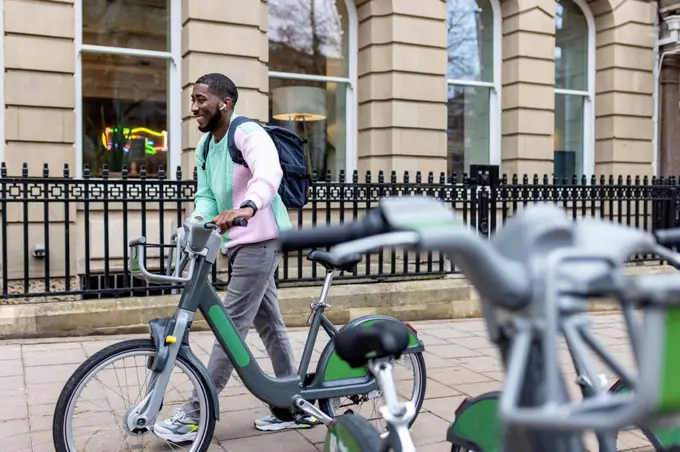 Happy man with electric bicycle walking on footpath