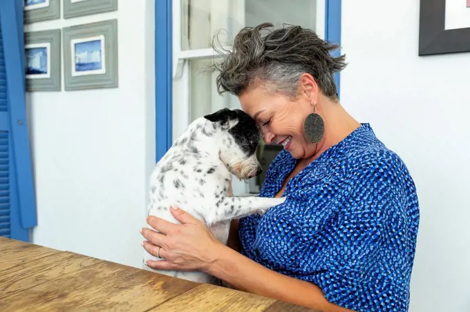 Happy woman embracing dog sitting at table