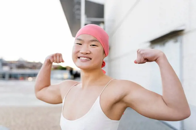 Happy woman wearing pink bandana showing biceps