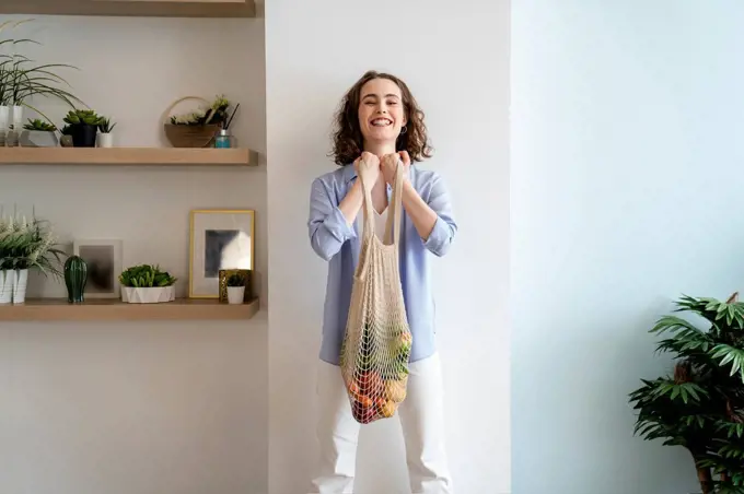 Young woman doing biceps with mesh bag at home