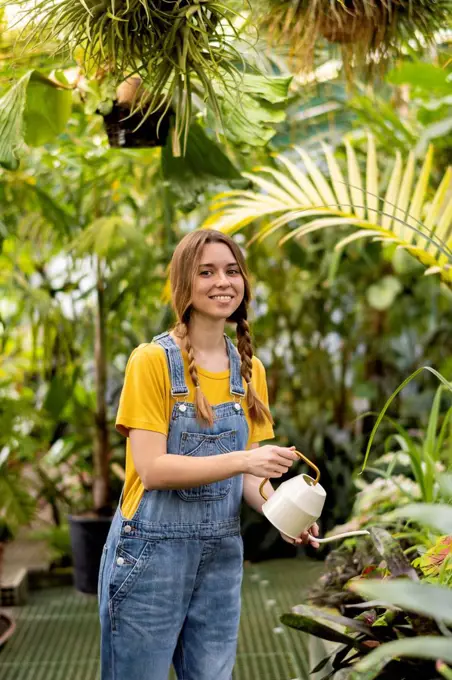 Happy woman watering plant in garden