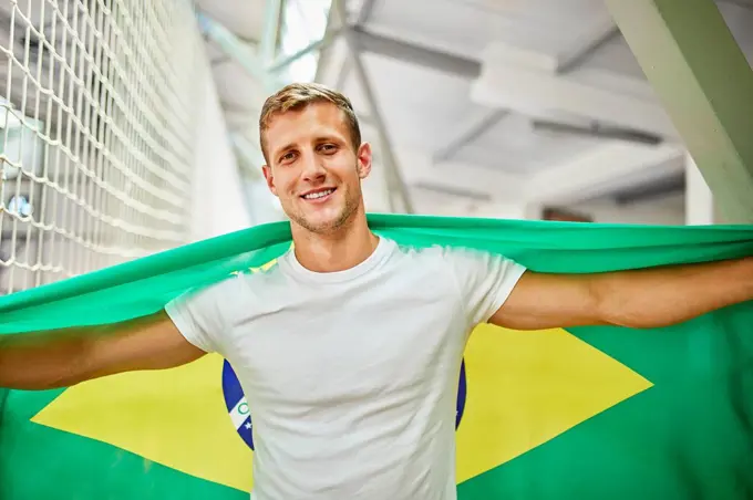 Smiling man holding Brazil Flag at sports event in stadium