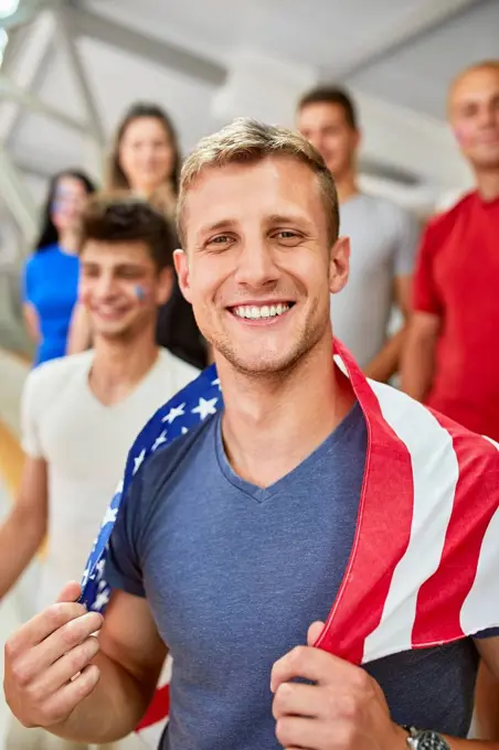 Smiling man holding American Flag in at sports event in stadium