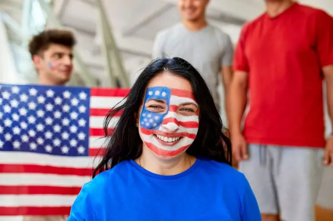 Smiling fan with American Flag face painted at sports event in stadium