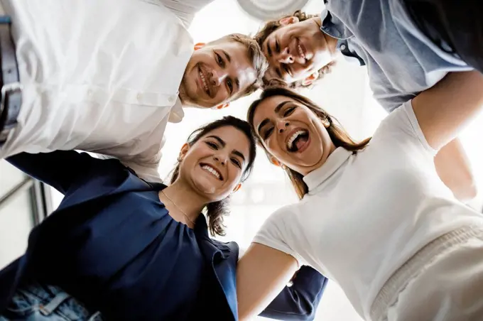 Happy business people huddling together in office