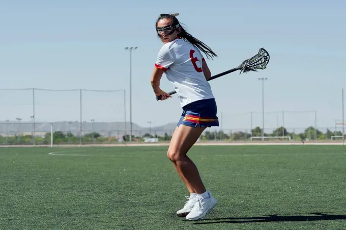 Player with lacrosse stick playing on sports field