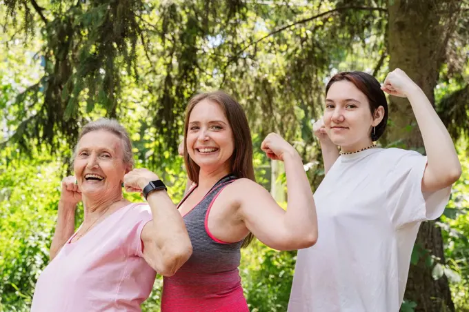 Active senior woman flexing muscles with daughter and granddaughter at park