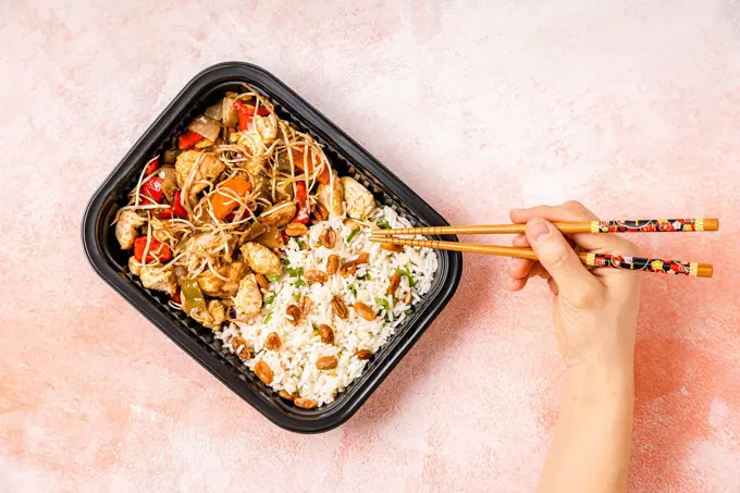 Personal perspective of woman eating take out chop suey