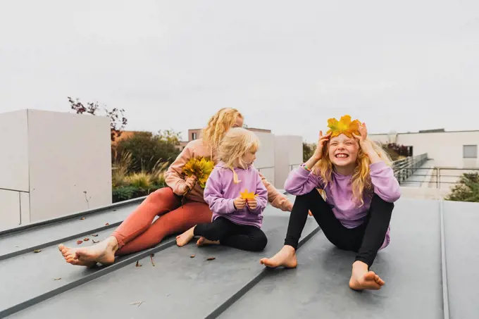 Happy family enjoying together with autumn leaves sitting at rooftop