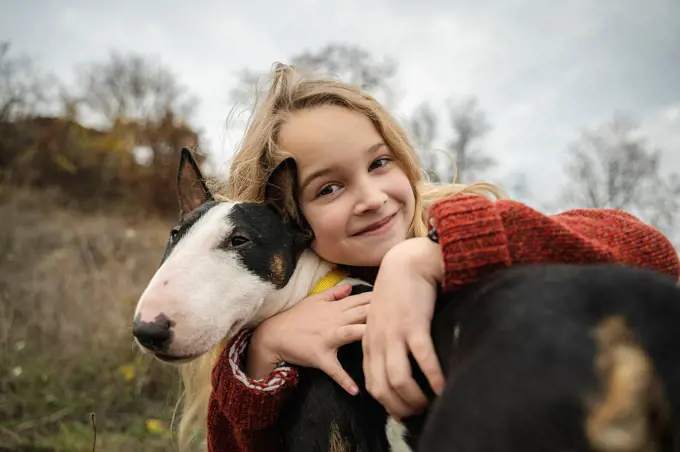 Smiling cute girl embracing dog