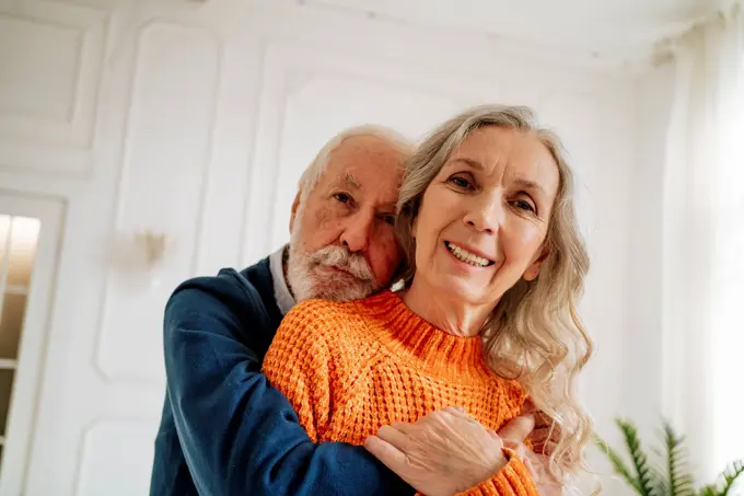 Loving senior couple embracing each other at home