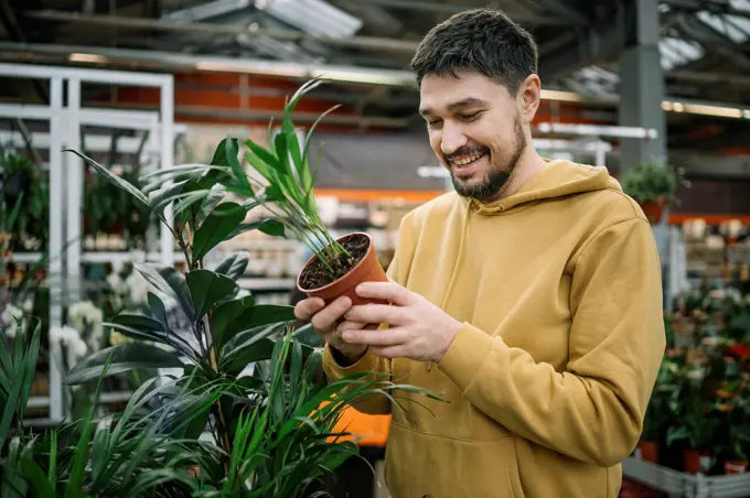 Happy man buying plant in garden center