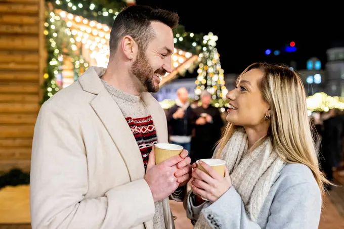 Happy man and woman with coffee cup at Christmas market