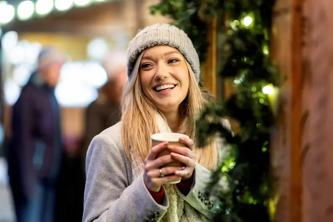 Happy young woman with coffee cup at Christmas market