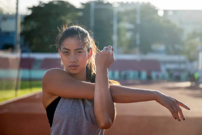 Young woman doing stretching exercise in sports field