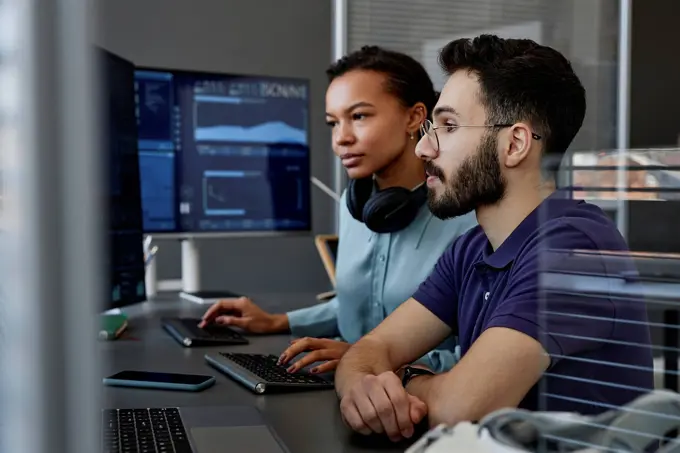 IT professionals working together on computers at desk