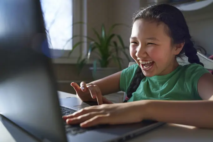 Happy girl having fun with laptop at home