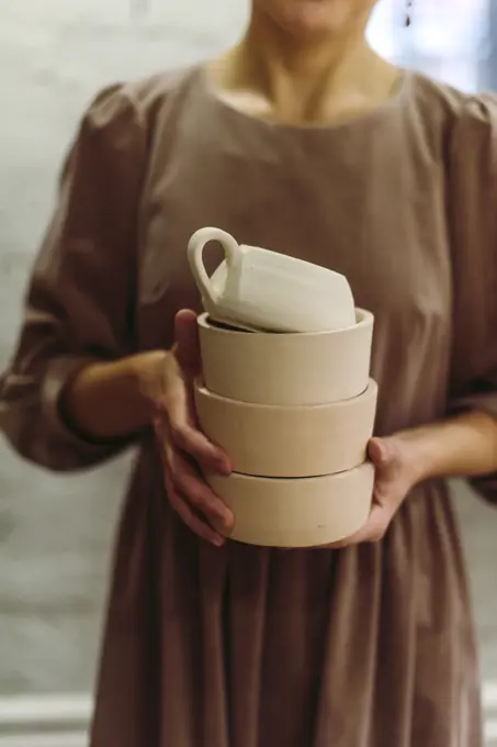 Potter holding handmade clay crockery in workshop