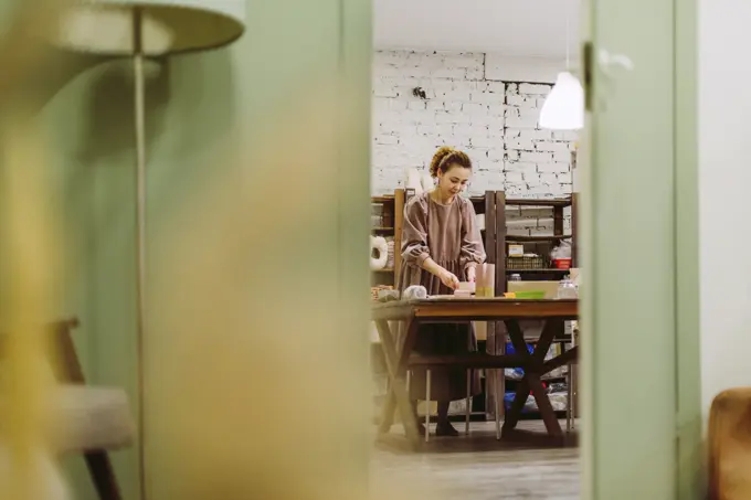 Reflection of businesswoman in mirror with crockery on desk at workshop