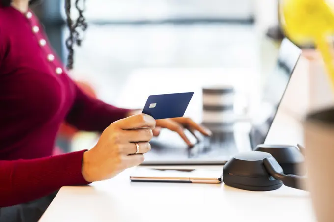 Businesswoman holding credit card and doing online shopping at office