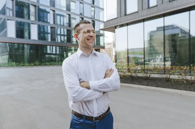 Confident businessman with arms crossed standing outside office building