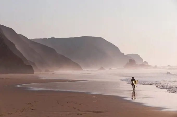 Portugal, Surfer walking on beach