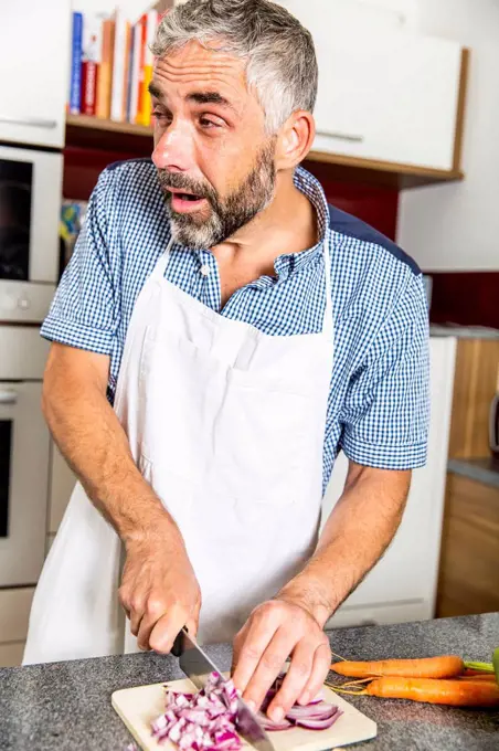 Austria, Man in kitchen chopping onions