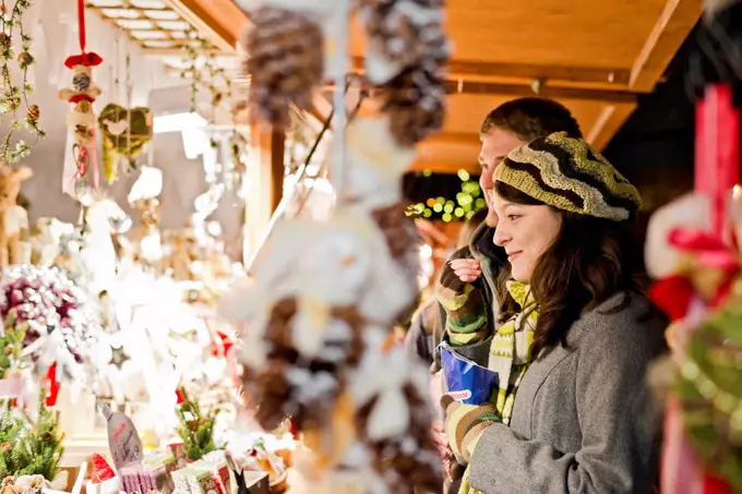 Germany, Berlin, young couple watching offerings at Christmas market