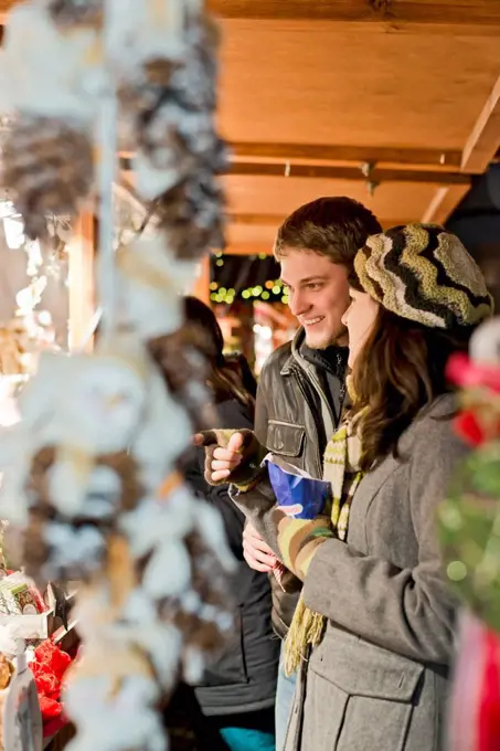 Germany, Berlin, young couple watching offerings at Christmas market