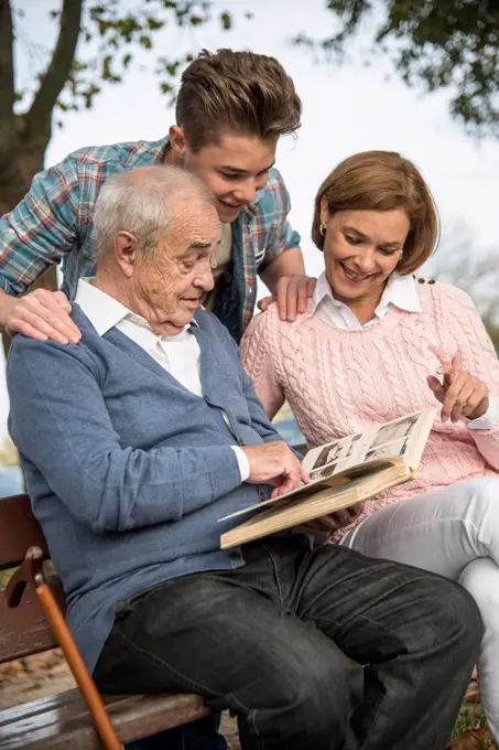 Senior man with grandson and daughter looking at photo album