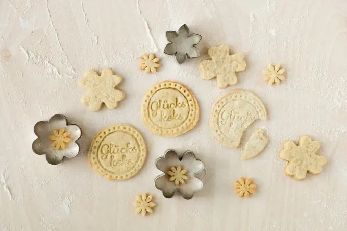 Home-baked fortune cookies and metal cookie cutters on light wood