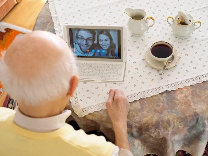 Grandfather videoconferencing with grandchildren via digital tablet