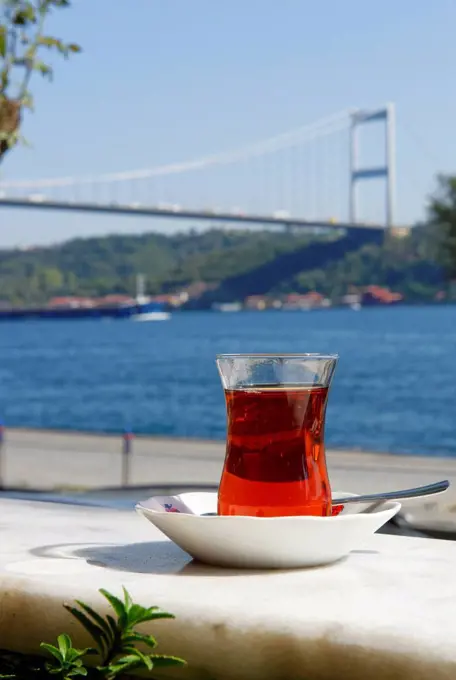 Turkey, Istanbul, glass of tea in front of Fatih Sultan Mehmet Bridge