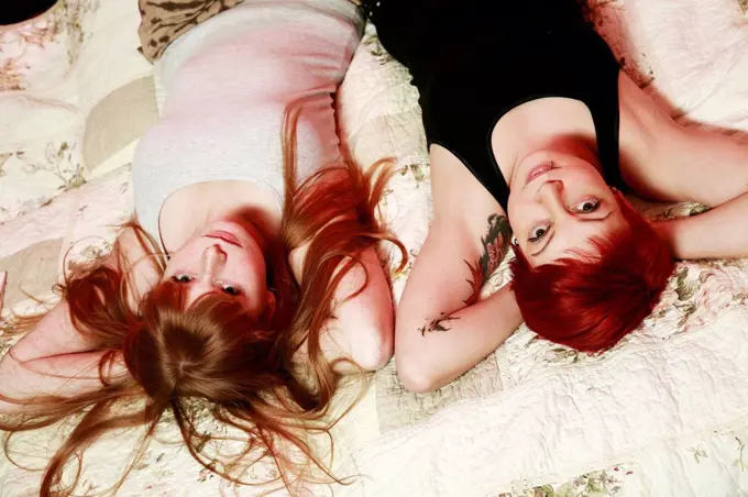 Portrait of two female friends relaxing on a blanket at home